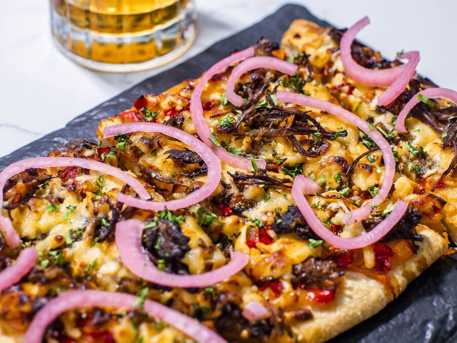 A pizza with toppings on a slate board.