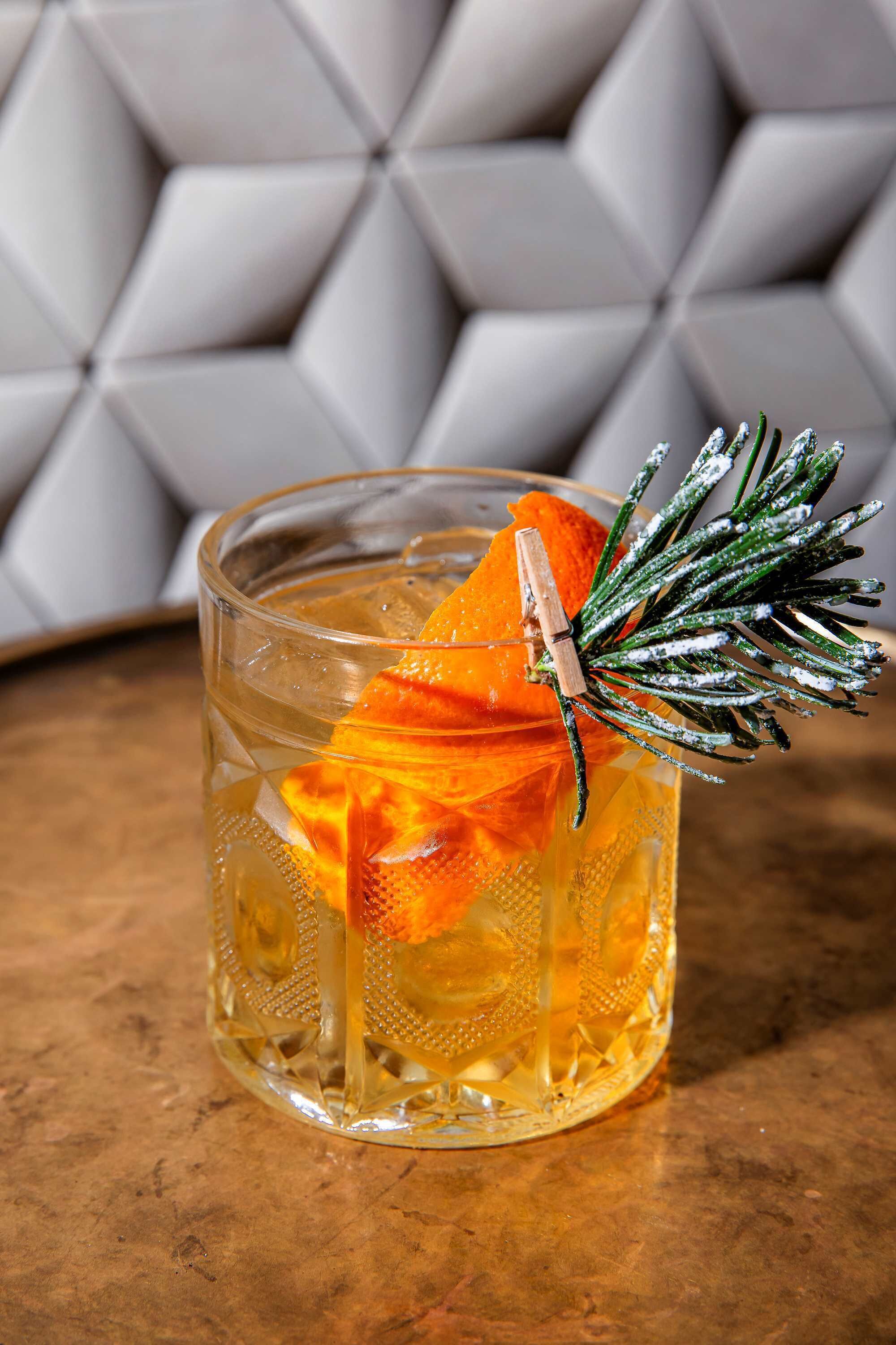 A clear glass with a decorative garnish on a textured surface.