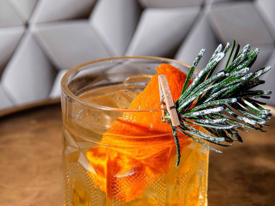 A clear glass with a decorative garnish on a textured surface.