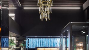 A modern hotel lobby with a reception desk labeled "Kindler Hotel," leather seating, a chandelier, and a wooden floor. - The Kindler Hotel (Lincoln)