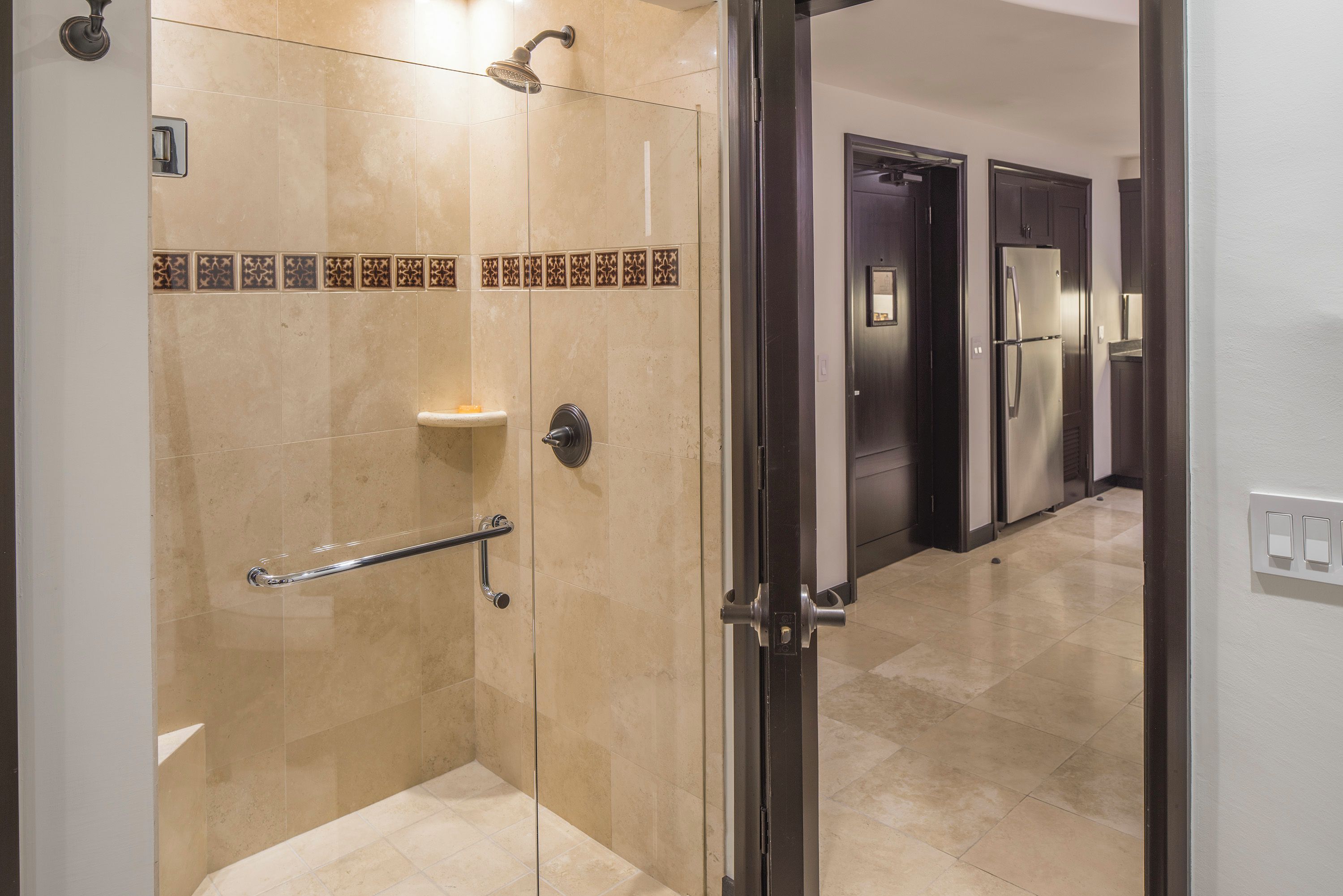 A modern bathroom with a shower, a handrail, and a tiled floor.