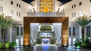 A modern hotel entrance with a central archway, palm trees, and a night sky. - Hilton Vacation Club Cabo Azul Los Cabos (San Jose del Cabo)