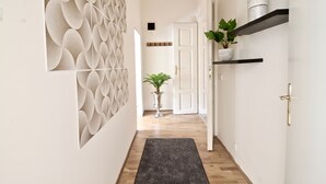 A hallway with a patterned wall, a potted plant, and a door at the end. - NEW DESIGN & STYLE Apartment Old Town XXL (Prague)