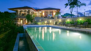 Una casa moderna con piscina, area salotto esterna e patio ben illuminato.