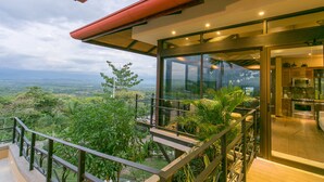 Una casa moderna con un balcone in vetro che si affaccia su un paesaggio lussureggiante.