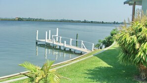 A calm lake with a dock extending into the water, surrounded by greenery and a clear sky. - Coast & Country Cabin 4 (Rainbow Reach)