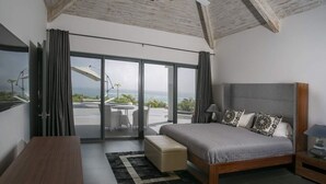 Un dormitorio moderno con una cama grande, un escritorio y vistas al exterior a través de una puerta corrediza de vidrio.