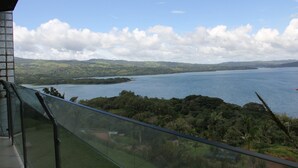 Vista de um varanda com vista para um lago, rodeado por vegetação e colinas.