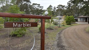 Uma placa de madeira com o nome 'Marbles' e um aviso de estacionamento abaixo.