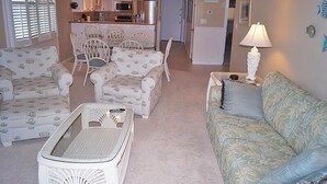A living room with patterned sofas, a coffee table, and a dining area with chairs. - Ocean Hideaway (Ocean City)