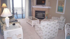 A living room with a fireplace, a television, and a balcony with a view. - Ocean Hideaway (Ocean City)