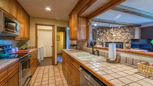 A kitchen with wooden cabinets, a stone backsplash, and a built-in dishwasher. - Cedar Lower Luxury Vacation At Windcliff 2 Bedroom Home by RedAwning (Estes Park)