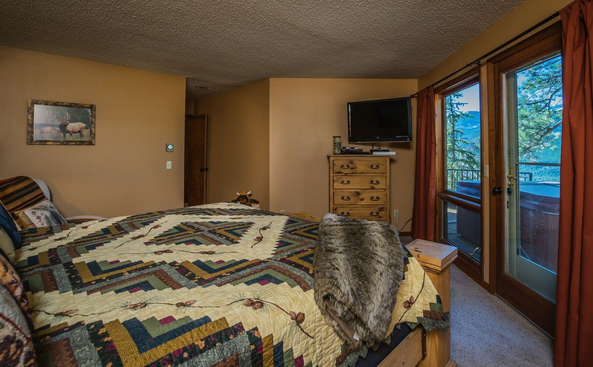 Una camera da letto con un letto grande, una televisione su un comò in legno e una finestra vista alberi.