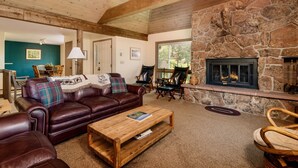 A cozy living room with a stone fireplace, leather furniture, and a view of the outdoors. - Adams Vacation At Windcliff 2 Bedroom Home by RedAwning (Estes Park)