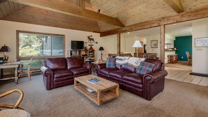 A spacious living room with leather sofas, a wooden coffee table, and a large window overlooking greenery. - Adams Vacation At Windcliff 2 Bedroom Home by RedAwning (Estes Park)