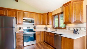 A kitchen with wooden cabinets, stainless steel appliances, and a tiled backsplash. - Kintzle Family Vacation At Windcliff 4 Bedroom Home by RedAwning (Estes Park)