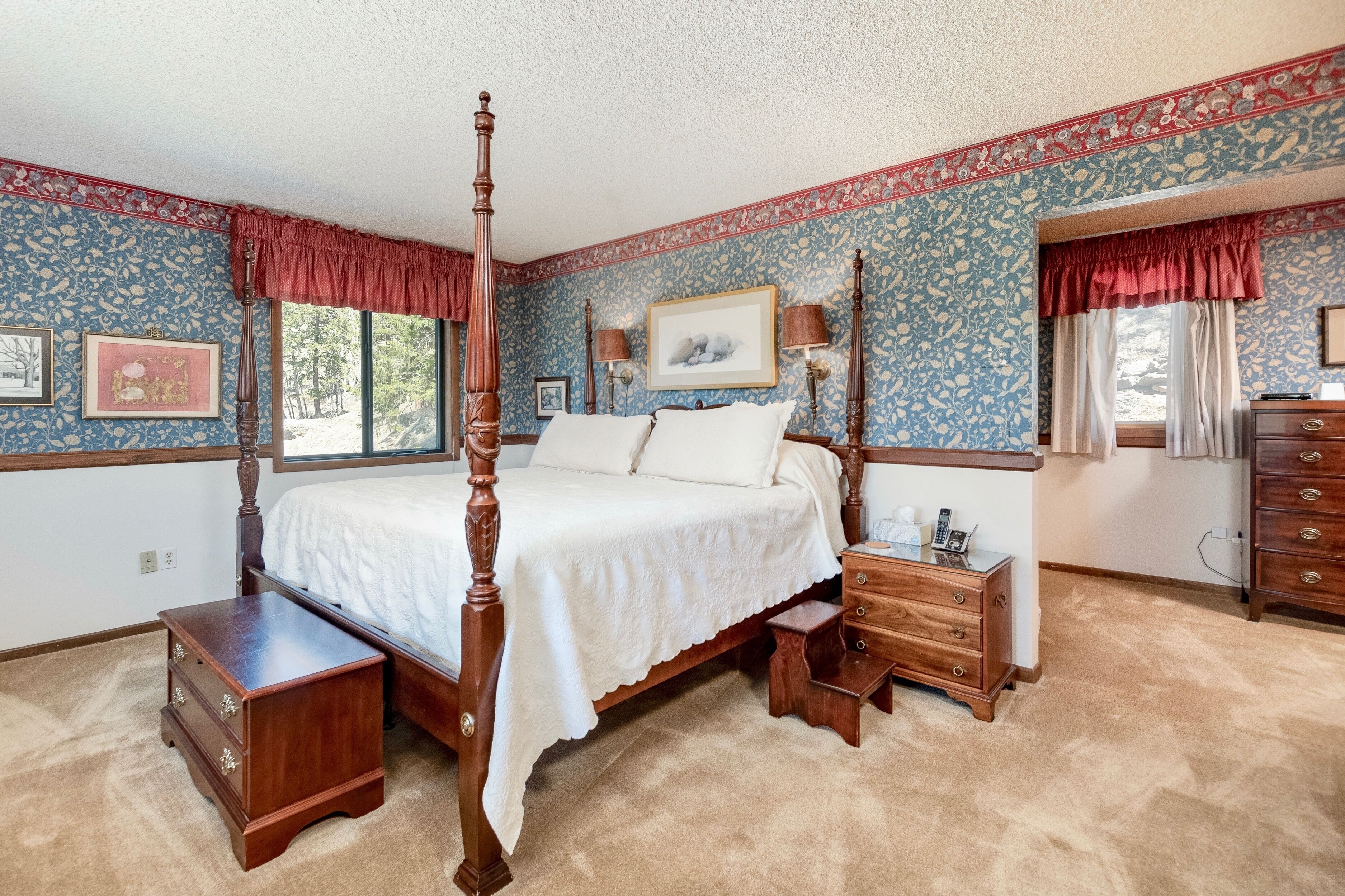 Une chambre à coucher avec un lit à baldaquin, une table de chevet, une commode et une fenêtre avec des rideaux.