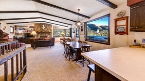 Amplia sala de estar con un gran comedor, una chimenea acogedora y una vista panorámica a las montañas a través de las ventanas.