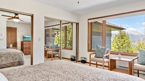 Ein Schlafzimmer mit großem Fenster, einem Bett, einem Schreibtisch und einem Stuhl.