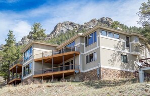 Una casa moderna de dos pisos con base de piedra, ventanas amplias y una terraza de madera.