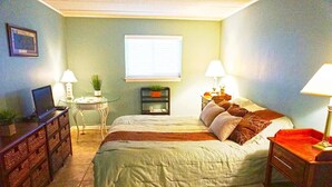 A bedroom with a bed, bedside tables, a desk, a chair, a lamp, and a window. - Thunder Island 128c 2 Bedroom Condo by RedAwning (Ocean City)