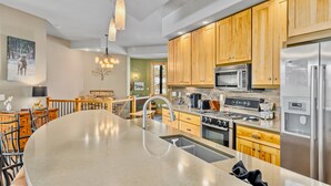 Una cocina moderna con armarios de madera, electrodomésticos de acero inoxidable y una isla grande con un lavamanos.