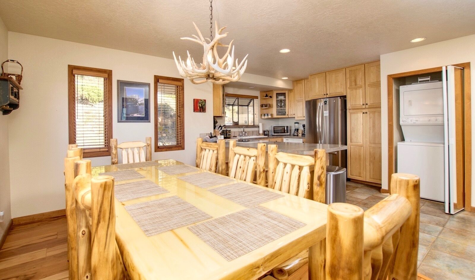A spacious kitchen with wooden cabinets, a stainless steel refrigerator, and a dining area with a large wooden table and chairs.