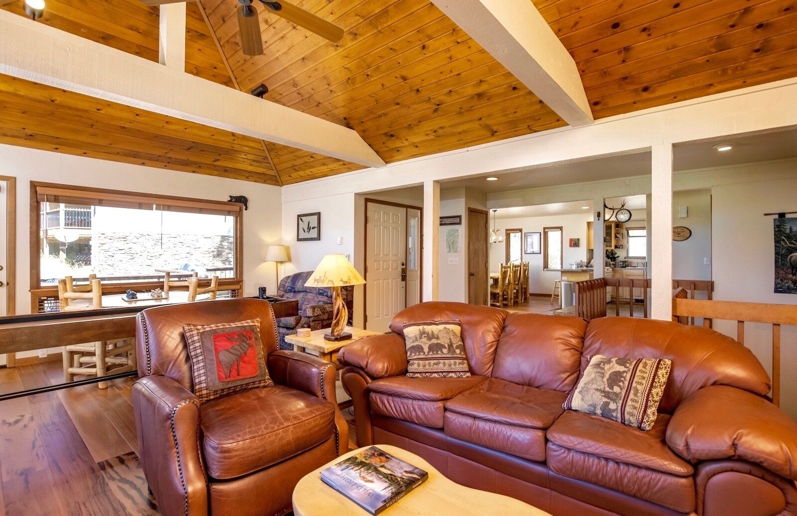Ein gemütliches Wohnzimmer mit Ledersofas, einem Couchtisch und einem Essbereich mit Holzmöbeln.