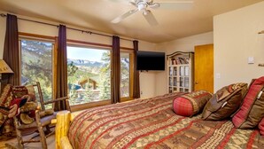 A bedroom with a large bed, a wooden chair, a bookshelf, and a TV.