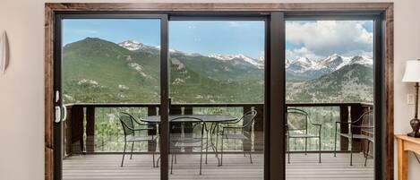 A balcony with a mountain view, featuring a table and chairs.