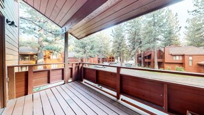 Eine Holzdielen-Terrasse mit Geländer, mit Blick auf eine Straße und Gebäude.