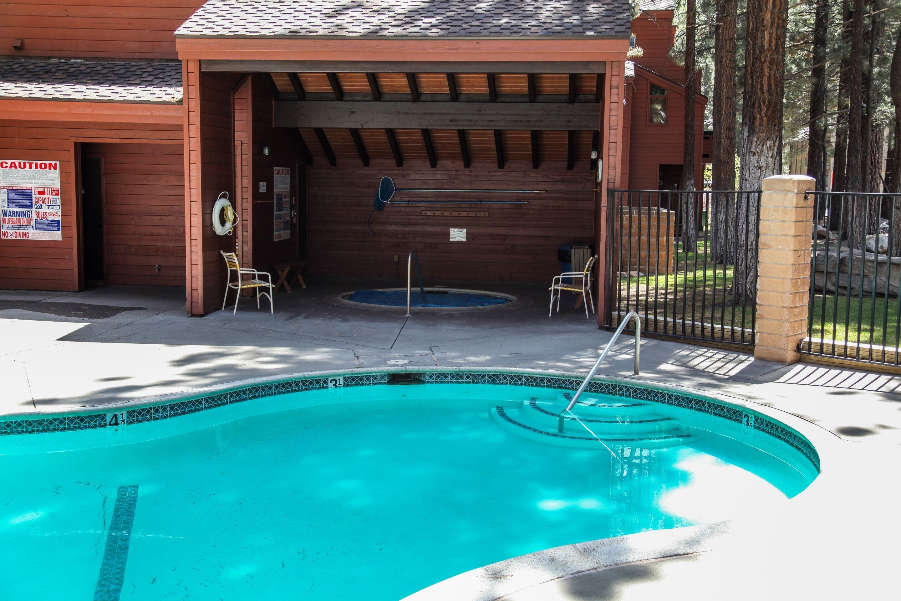 A pool area with a wooden deck, a hot tub, and a covered seating area.