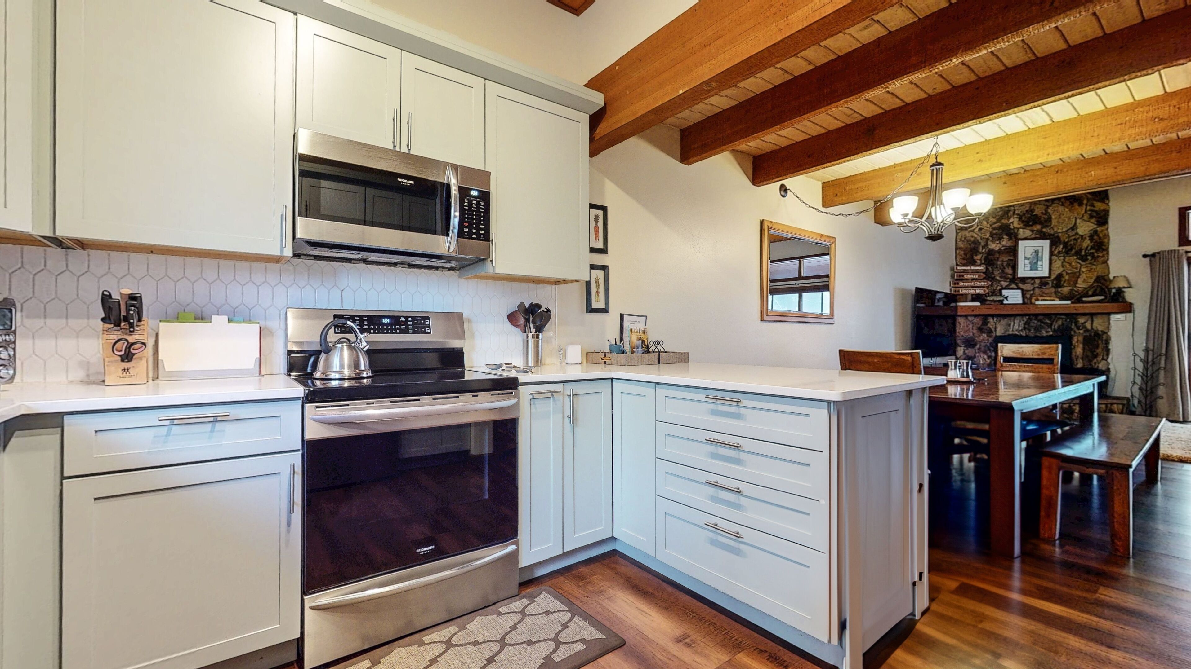 A modern kitchen with white cabinetry, a stainless steel range, and a built-in oven.