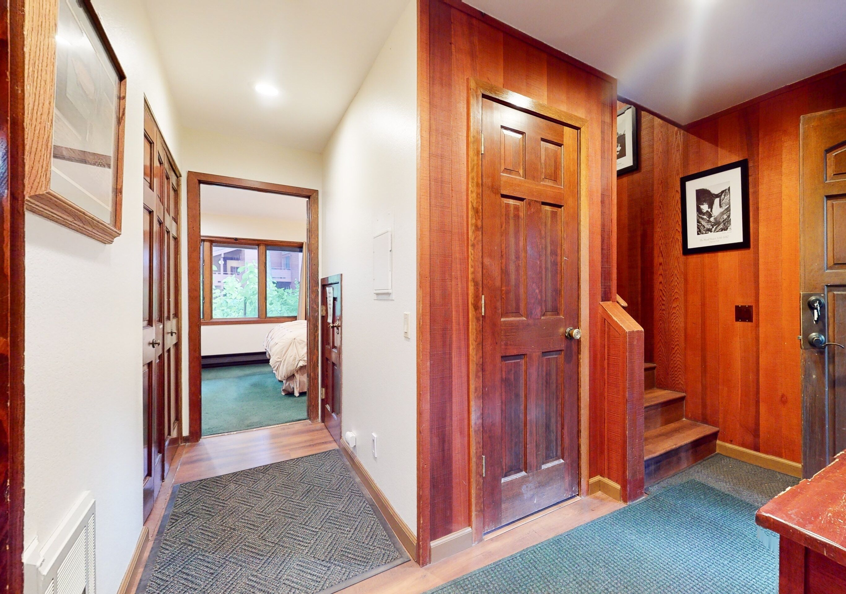 A hallway with wooden doors and a staircase leading to a bedroom.