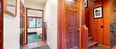 A hallway with wooden doors and a staircase leading to a bedroom.