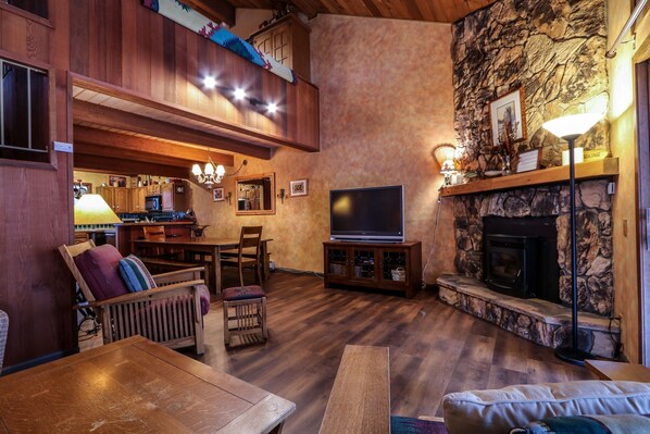 Un salon chaleureux avec une cheminée en pierre, des meubles en bois et un téléviseur à écran plat.