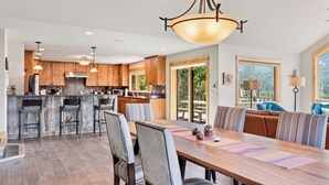 Una cocina amplia con armarios de madera, una isla central con taburetes y un comedor con una mesa grande y sillas.