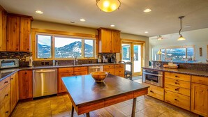 Una cocina moderna con armarios de madera, una isla grande y vistas a montañas a través de las ventanas.