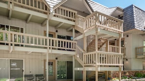 A multi-story building with a balcony, a staircase, and a stone wall with flowers. - Timber Ridge Unit 2e 1 Bedroom Condo by RedAwning (Aspen)