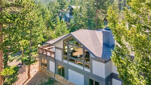 A modern house with a large glass facade, stone foundation, and a balcony overlooking a forested area. - Werlein Family Vacation At Windcliff 4 Bedroom Home by RedAwning (Estes Park)