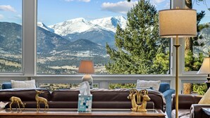 A living room with a view of snow-capped mountains, a brown leather sofa, decorative items, and a lamp. - Werlein Family Vacation At Windcliff 4 Bedroom Home by RedAwning (Estes Park)