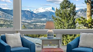A room with two blue armchairs, a small table with a lamp, and a view of snow-capped mountains through large windows. - Werlein Family Vacation At Windcliff 4 Bedroom Home by RedAwning (Estes Park)