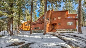 A rustic cabin with a stone foundation, wooden exterior, and a staircase leading to a deck. - Your Roomy Northstar Retreat Awaits by RedAwning (Truckee)