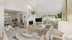 A spacious living room with a fireplace, comfortable seating, and a TV.