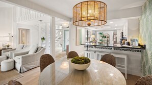 A modern living room with a round dining table, white sofas, and a hanging light fixture.