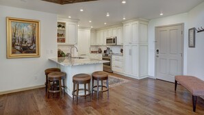A spacious kitchen with white cabinets, a large island with stools, and a painting on the wall. - 2br In The Seasons At Arrowhead-vaulted Ceilings 2 Bedroom Condo by RedAwning (Edwards)