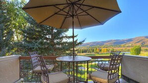 A deck with a table and chairs, an umbrella, and a scenic view of a valley and mountains. - 2br In The Seasons At Arrowhead-vaulted Ceilings 2 Bedroom Condo by RedAwning (Edwards)