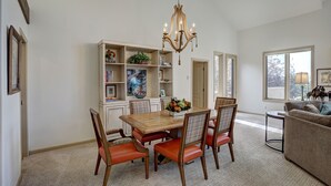 A dining area with a wooden table and chairs, a chandelier, and a bookshelf with decorative items. - 2br In The Seasons At Arrowhead-vaulted Ceilings 2 Bedroom Condo by RedAwning (Edwards)
