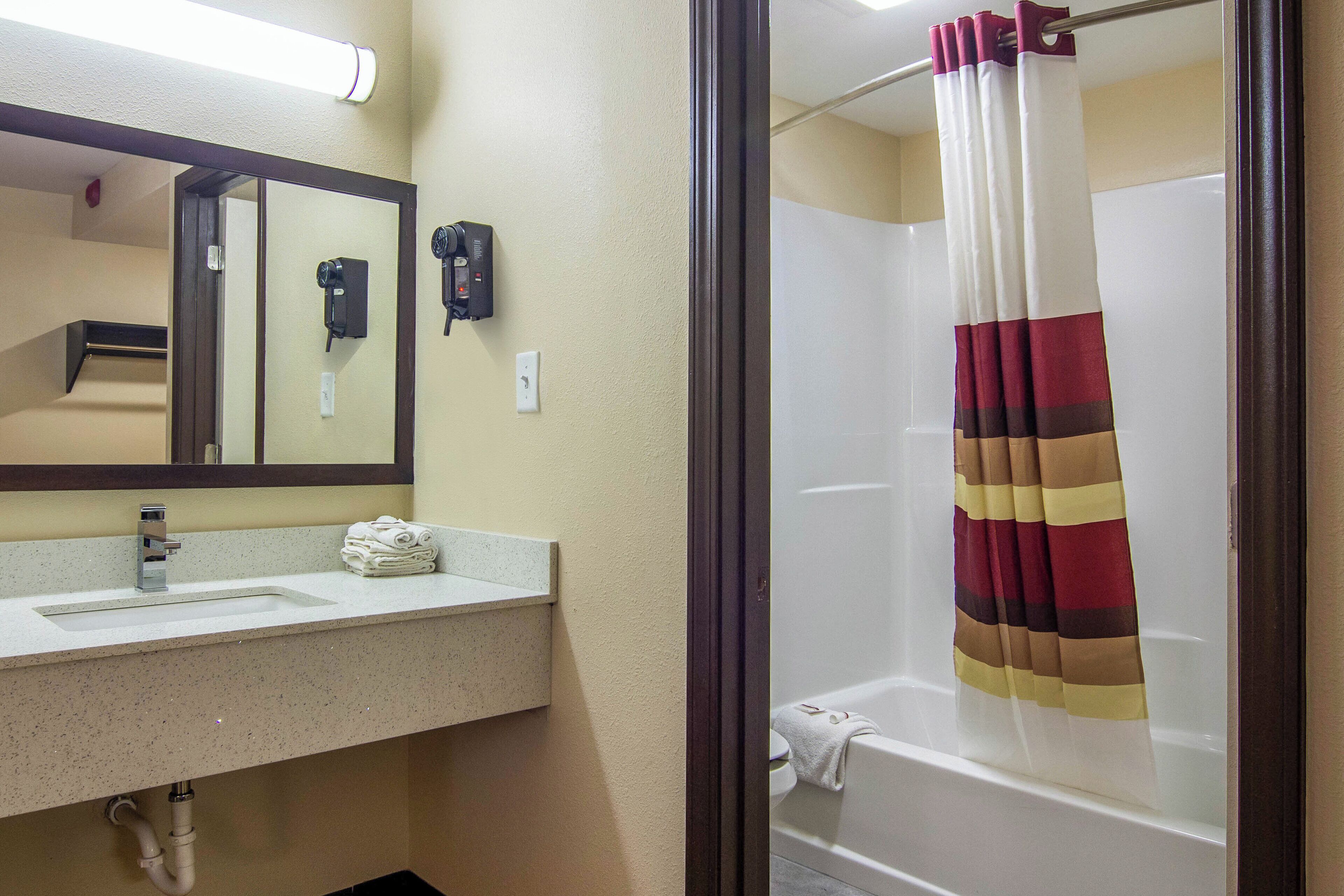A bathroom with a sink, mirror, hair dryer, and a shower curtain.