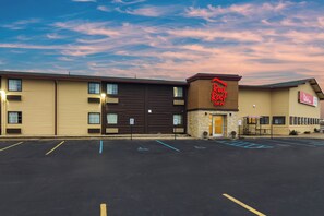 A Red Roof Inn with a parking lot, a covered outdoor seating area, and a clear sky. - Red Roof Inn Perrysburg (Perrysburg)